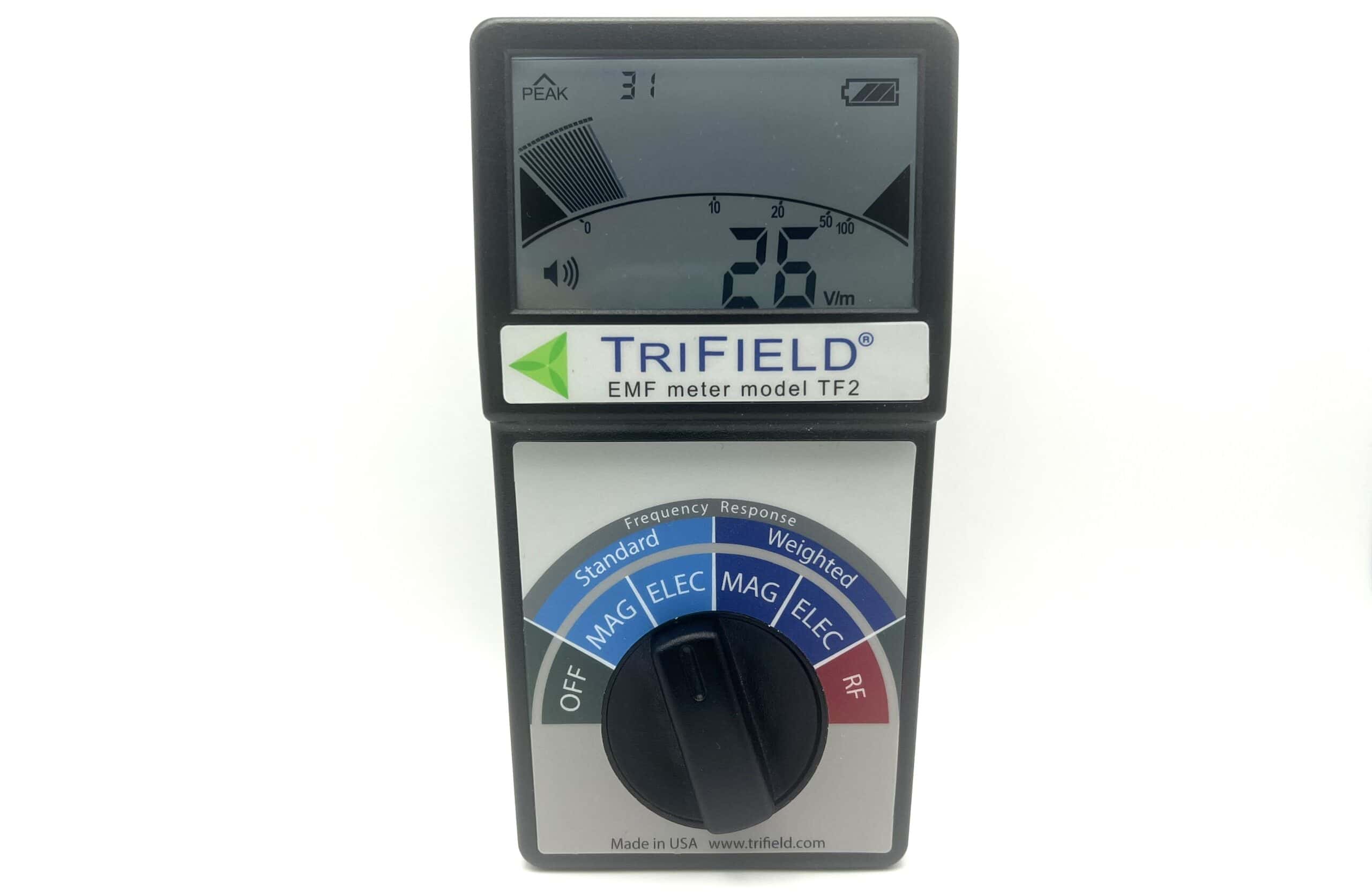 A TriField EMF meter model TF2 with digital display showing a reading of 26 Vm. The dial is set to measure magnetic fields in the standard mode.