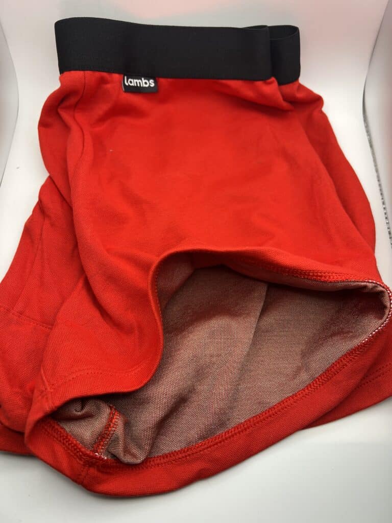 Red shorts with a black waistband, labeled lambs, displayed on a white surface.