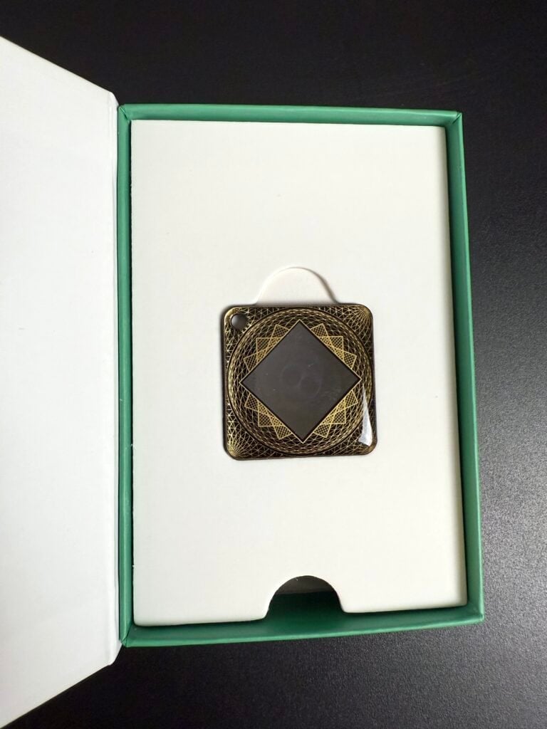 A decorative square emblem with intricate geometric patterns in a green box packaging.