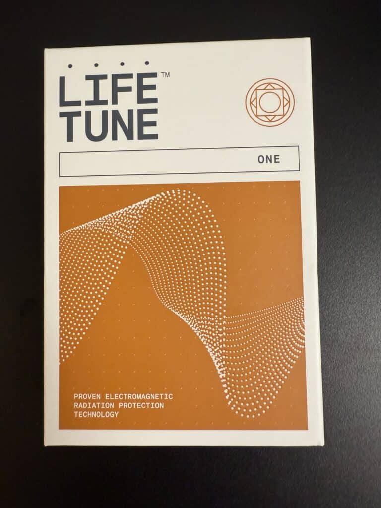 Box labeled LIFE TUNE ONE with a geometric wave design and text stating Proven Electromagnetic Radiation Protection Technology on a black background.