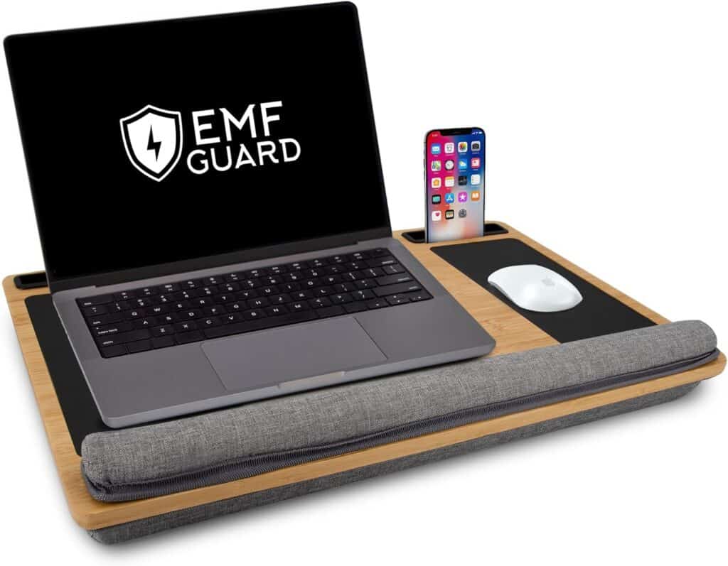 Laptop desk with a laptop displaying EMF Guard on the screen, a smartphone, a mouse on a pad, and a gray wrist cushion.