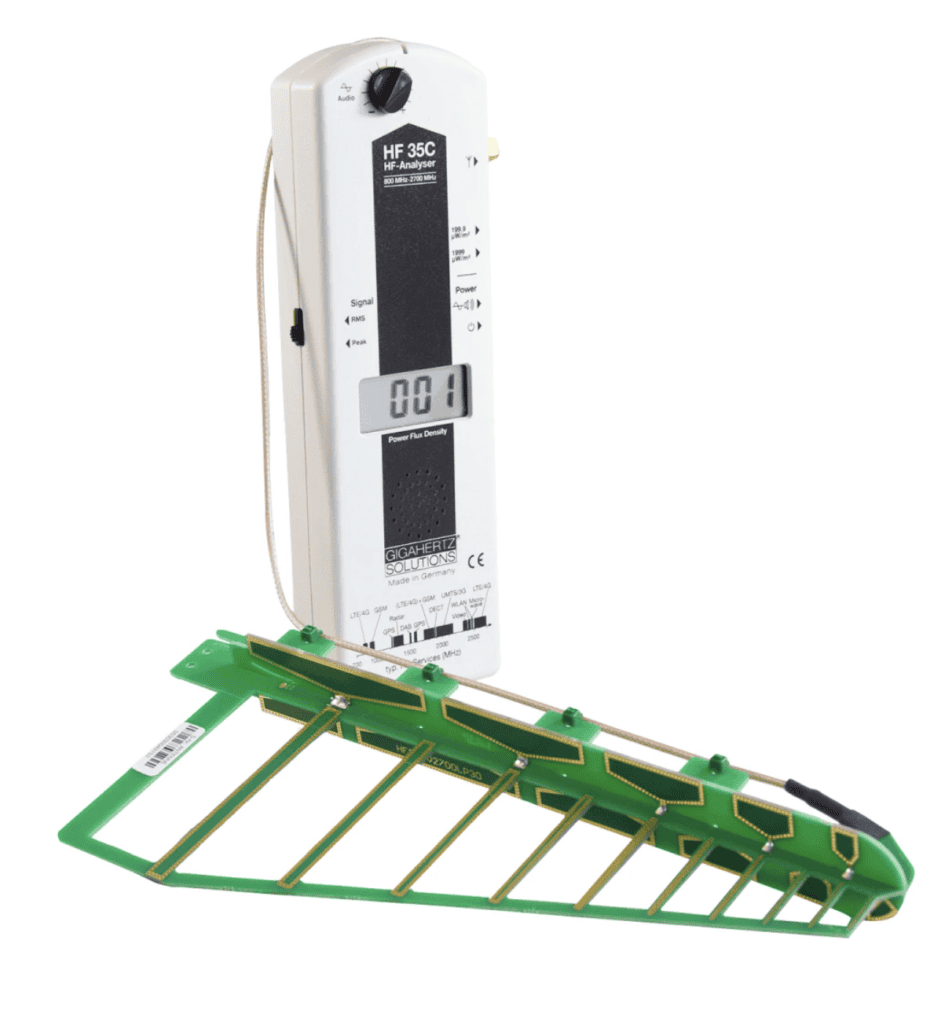 Screenshot 2026-02-11 at 111955 AM - EMF Academy White handheld RF meter with digital display and attached green/yellow directional antenna, used for measuring high-frequency electromagnetic fields.