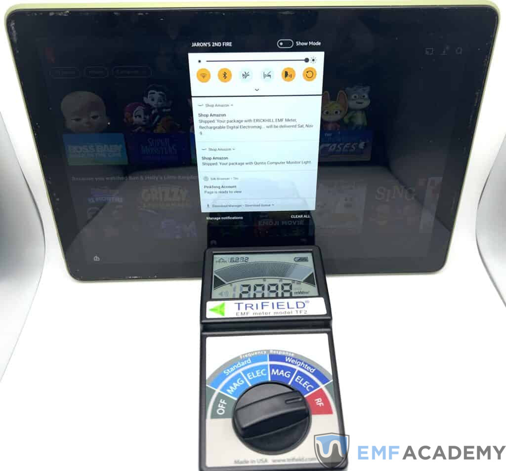 A tablet displaying a screen next to a Trifield EMF meter showing a reading.