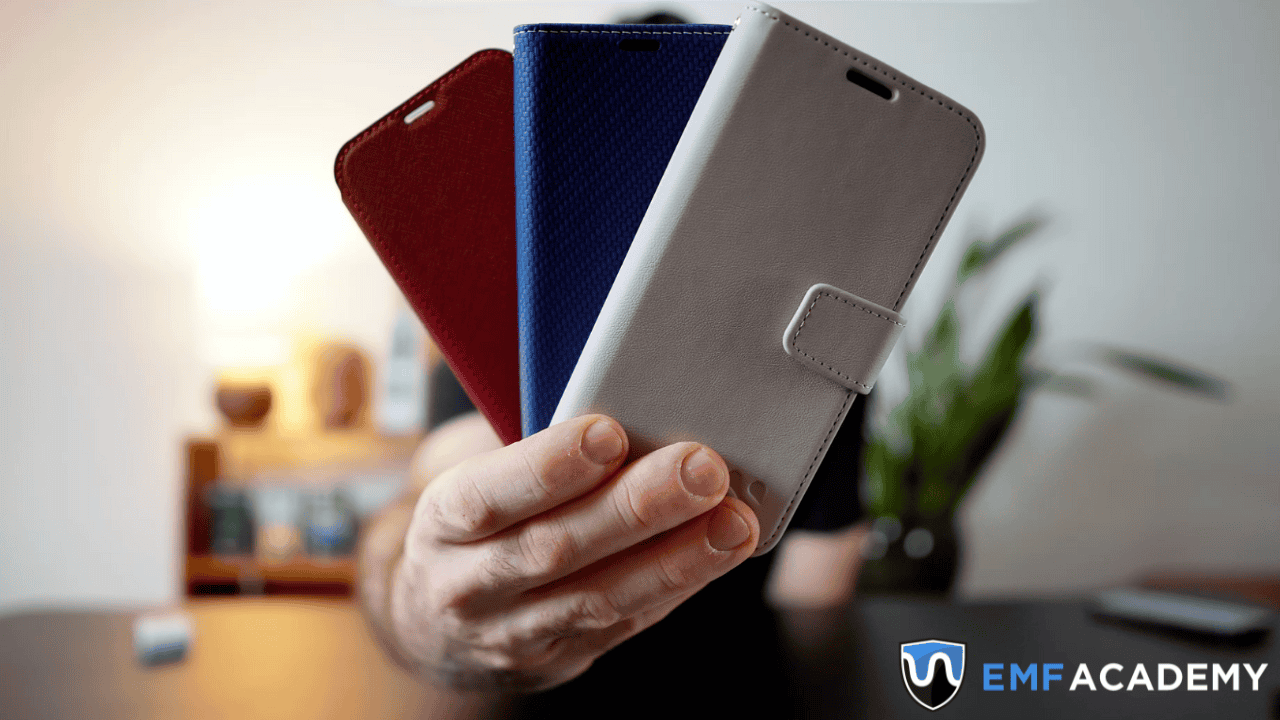 A person holds three smartphone cases in red, blue, and gray against a blurred background.