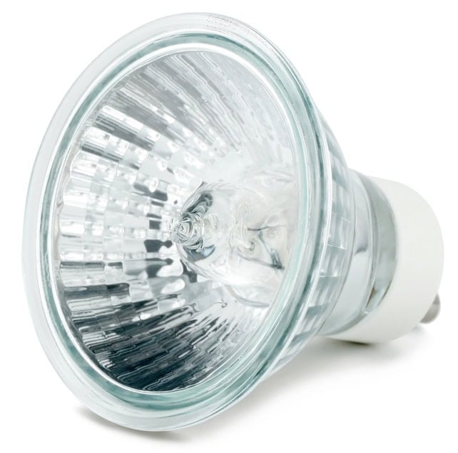 Close-up of a halogen light bulb with a glass reflector and two metal prongs for connection.