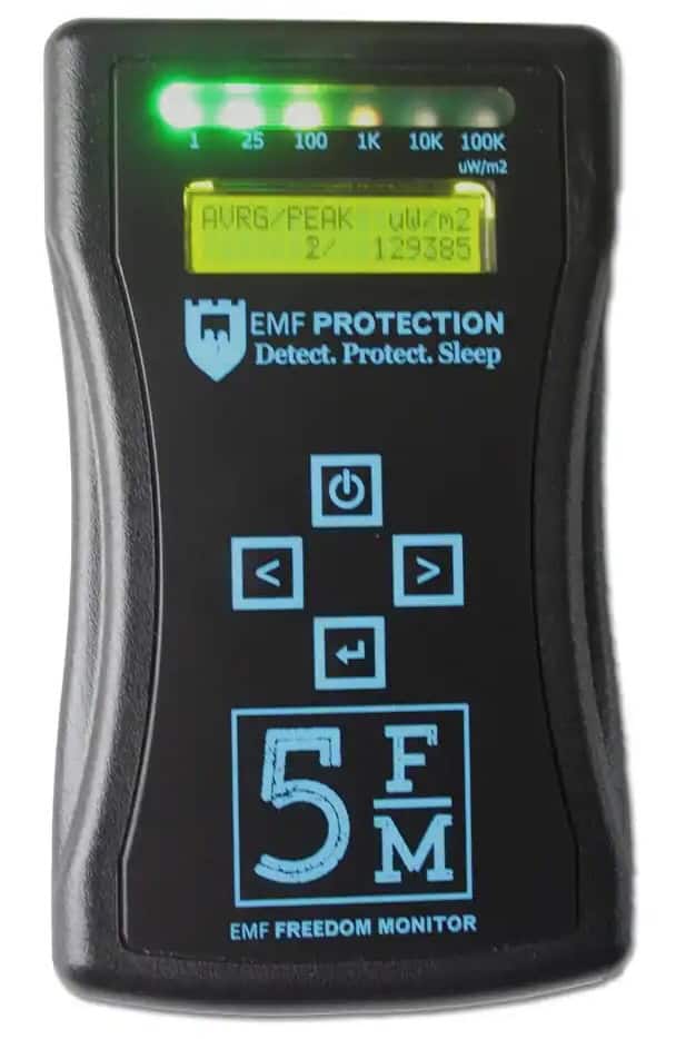A handheld EMF detector device displays readings on a small screen with illuminated indicator lights and navigation buttons on its front panel.